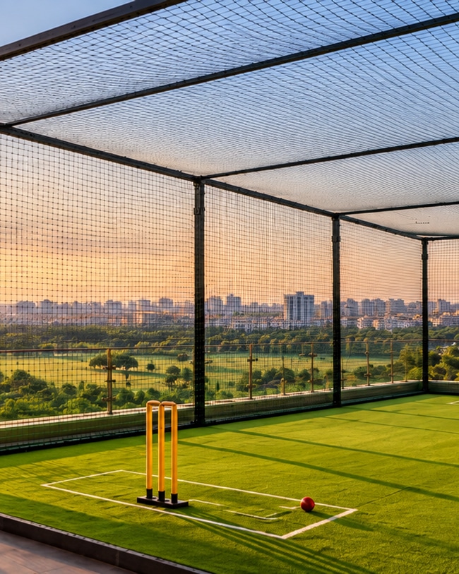 Rooftop cricket practice net with a turf pitch at sunset